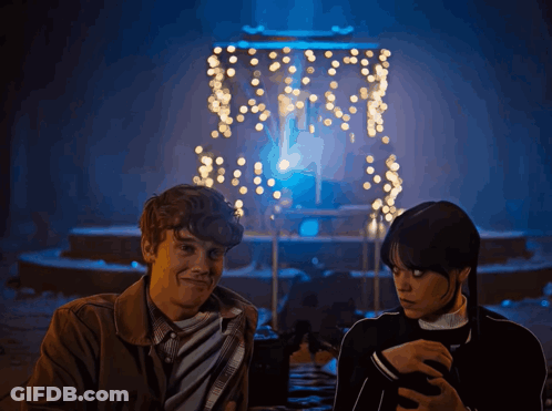 Man And Woman In Front Of Christmas Lights GIF