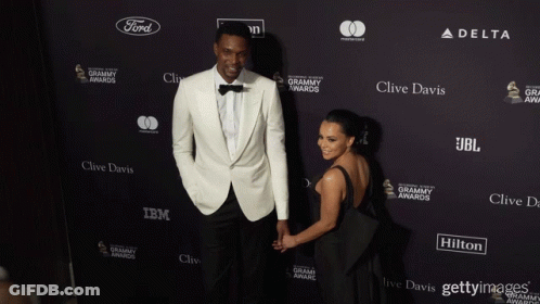 Man And Woman In Front Of Clive Davis IBM JBL Wall GIF