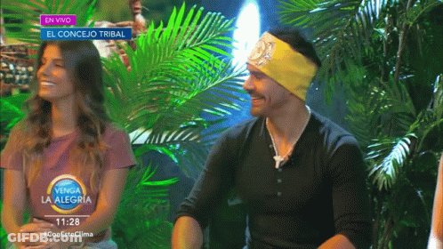 Man And Woman In Front Of En Vivo Sign GIF