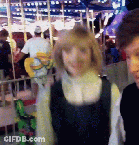 Man And Woman In Front Of Ferris Wheel GIF