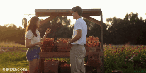 Man And Woman In Front Of Fruit Stand GIF