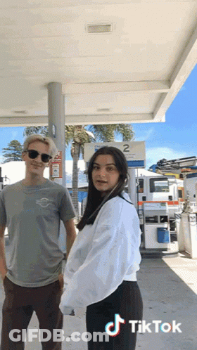 Man And Woman In Front Of Gas Station Sign 2 GIF
