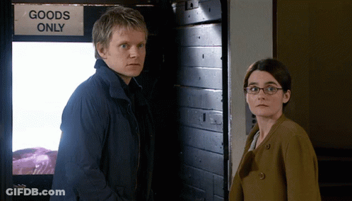 Man And Woman In Front Of Goods Only Door GIF