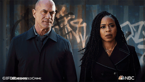 Man And Woman In Front Of Graffiti Wall Saying Organized Crime GIF