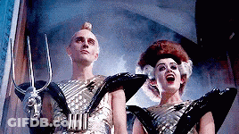 Man And Woman In Futuristic Costumes Holding Trident GIF
