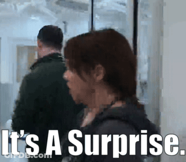 Man And Woman In Hallway Saying It's A Surprise GIF