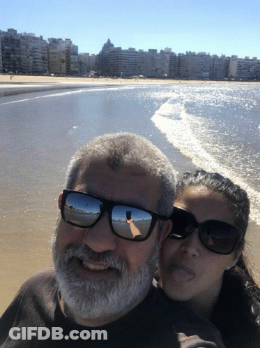 Man And Woman In Sunglasses Posing On Beach GIF