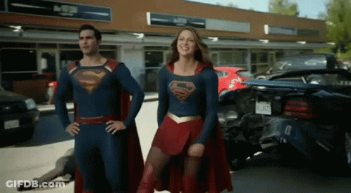 Man And Woman In Superman Costumes Standing In Front Of Store GIF
