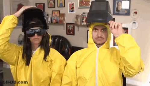 Man And Woman In Yellow Suits And Welding Helmets GIF