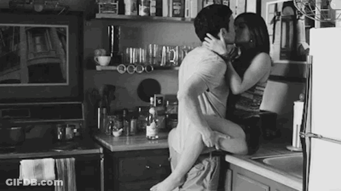 Man And Woman Kissing In Black And White Kitchen GIF