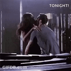 Man And Woman Kissing In Dark Room In Front Of Mirror GIF