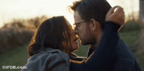 Man And Woman Kissing In Field With Sun Shining Through Eyes GIF