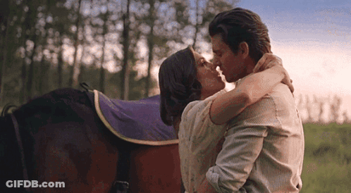 Man And Woman Kissing In Front Of A Horse In A Field GIF