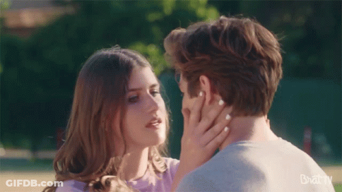 Man And Woman Kissing In Front Of Bazaar Banner GIF
