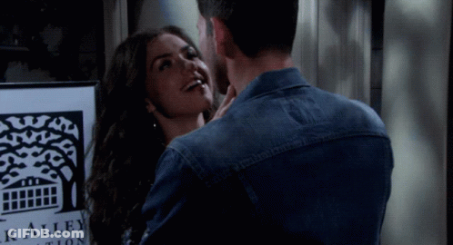 Man And Woman Kissing In Front Of Black Alley Auction Sign GIF