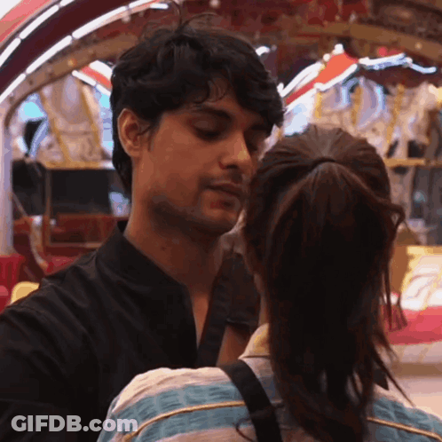 Man And Woman Kissing In Front Of Carousel GIF
