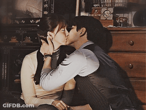 Man And Woman Kissing In Front Of Dresser GIF