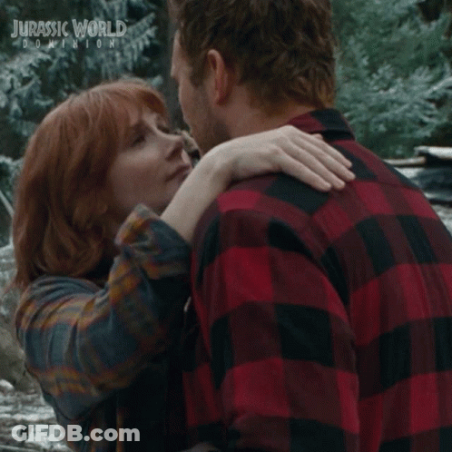 Man And Woman Kissing In Front Of Jurassic World Dominion Poster GIF