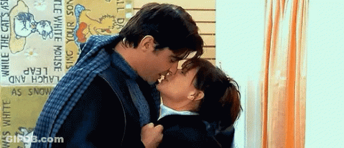 Man And Woman Kissing In Front Of Laughing Cats Sign GIF