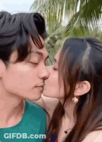 Man And Woman Kissing In Front Of Palm Trees GIF