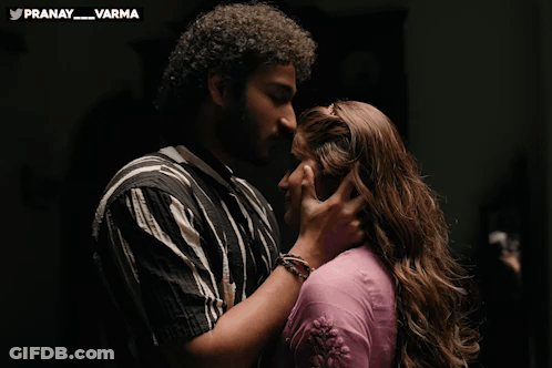 Man And Woman Kissing In Front Of Pranay Varma Banner GIF