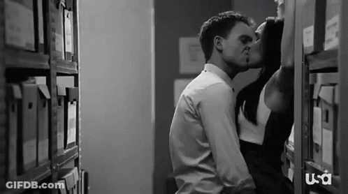 Man And Woman Kissing In Library GIF