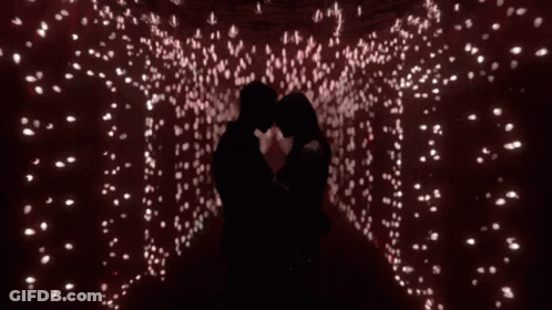 Man And Woman Kissing In Room With Lots Of Lights GIF
