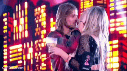 Man And Woman Kissing On Stage In Front Of City Skyline GIF