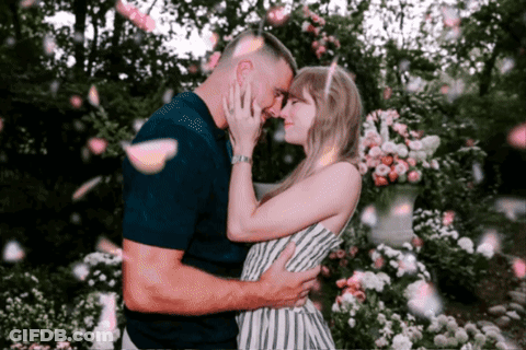 Man And Woman Kissing Under Falling Petals GIF