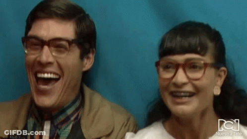 Man And Woman Laughing In Front Of Blue Wall GIF