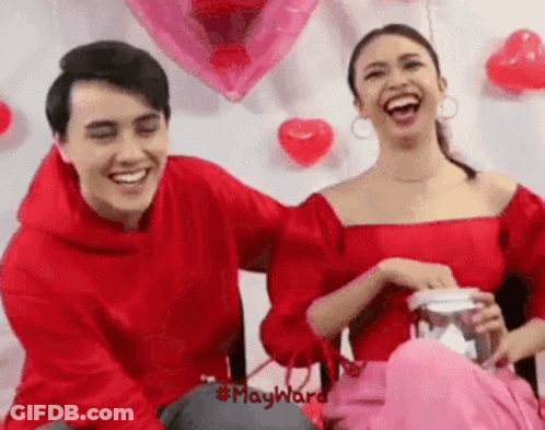 Man And Woman Laughing With Balloons And Hearts GIF