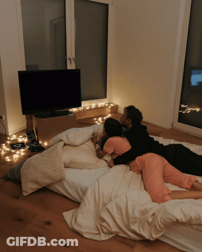 Man And Woman Laying On Bed In Front Of TV GIF