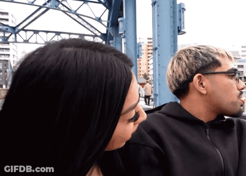 Man And Woman Looking At Each Other In Front Of Bridge GIF