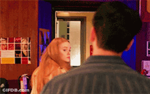 Man And Woman Looking At Each Other In Front Of Fire Extinguisher GIF