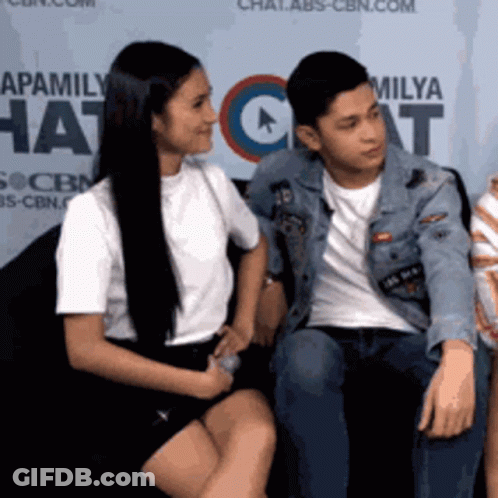 Man And Woman Next To Apamily Hat Sign GIF