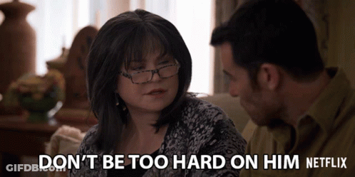 Man And Woman On Couch Woman Says Don't Be Too Hard On Him GIF