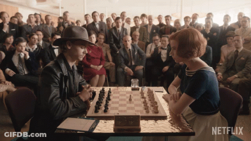 Man And Woman Playing Chess By Netflix Sign GIF
