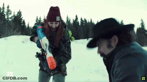 Man And Woman Playing Water Guns In Snow, Woman Wearing Beanie Saying No GIF