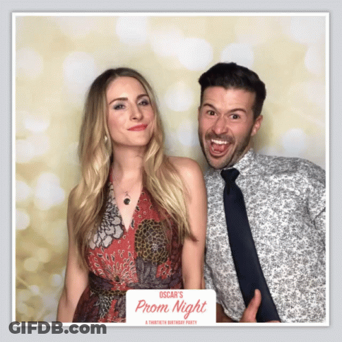 Man And Woman Pose In Front Of Prom Night Photo Booth GIF