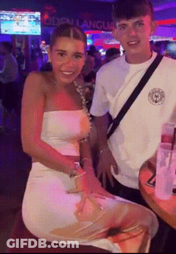 Man And Woman Posing In Front Of Don Langues Sign GIF