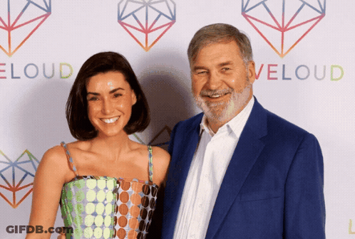 Man And Woman Posing In Front Of Eloud Wall GIF