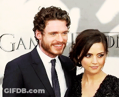 Man And Woman Posing In Front Of Game Sign GIF