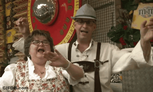 Man And Woman Posing In Front Of M&M Sign GIF