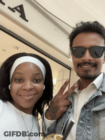 Man And Woman Posing In Front Of Sign GIF
