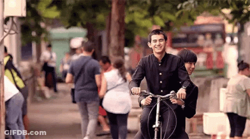 Man And Woman Riding Bike Down Street GIF