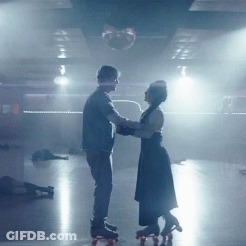 Man And Woman Rollerblading In Dark Room GIF