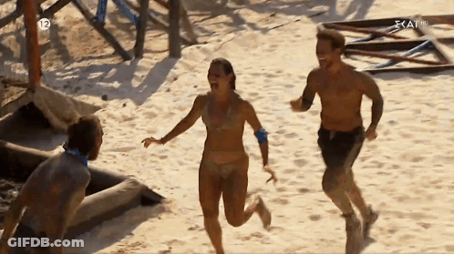 Man And Woman Running On Sandy Beach With Number 12 GIF