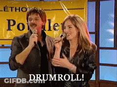 Man And Woman Singing In Front Of Poville Sign GIF