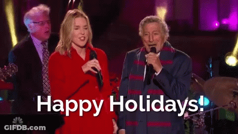 Man And Woman Singing Into Microphones Happy Holidays GIF