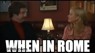 Man And Woman Sitting At Table Saying When In Rome GIF
